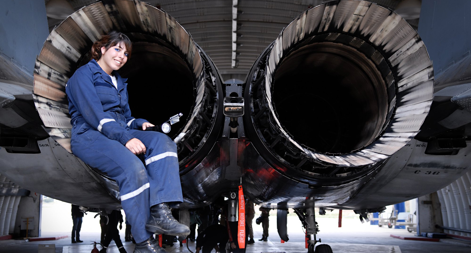 a mechanic sitting in the engine of a jet